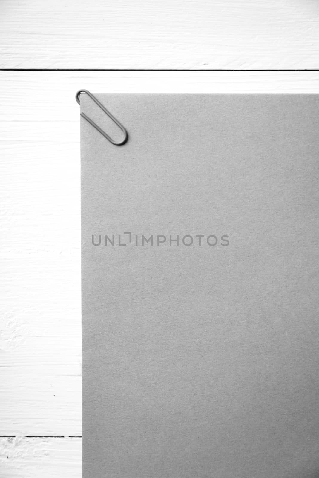 brown paper with green paper clip over white table black and white color