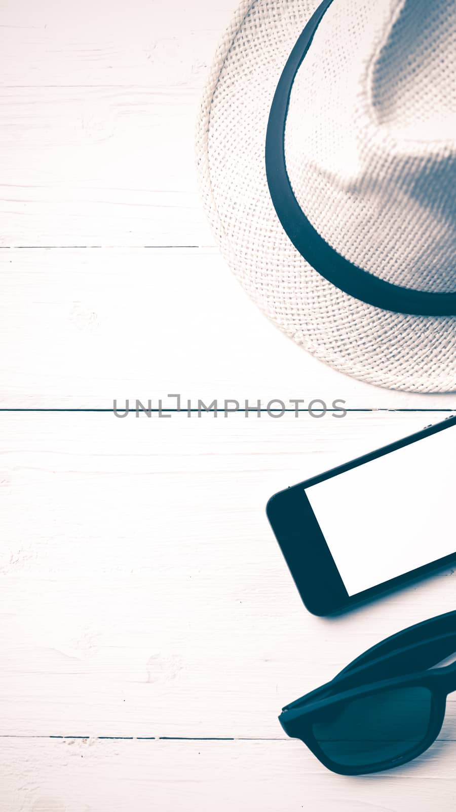 hat sunglasses and smart phone on white table vintage style