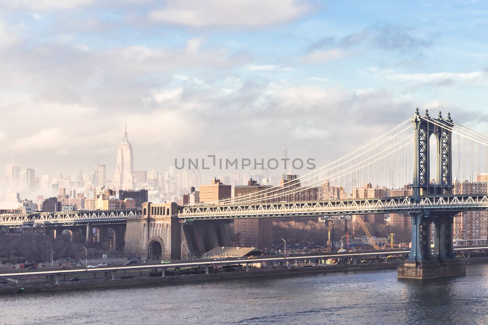 Manhattan bridge and New York City downtown skyline with Chrysler building and skyscrapers illuminated over East River panorama. Horizontal composition.