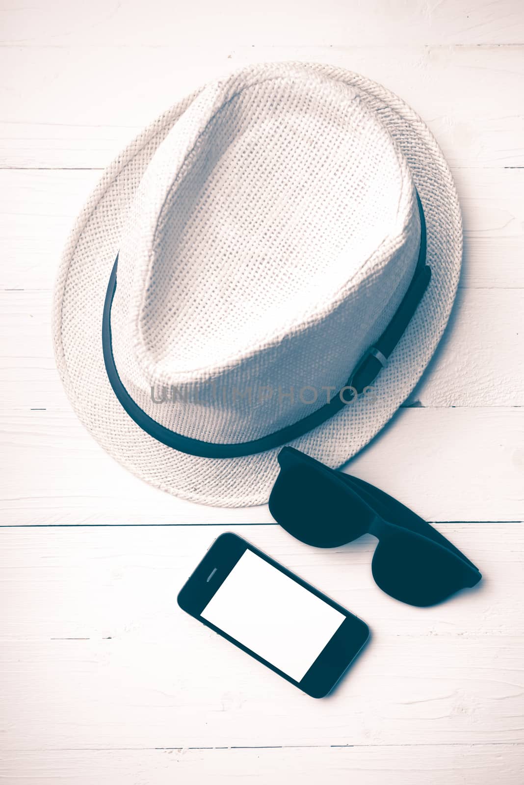 hat sunglasses and smart phone on white table vintage style