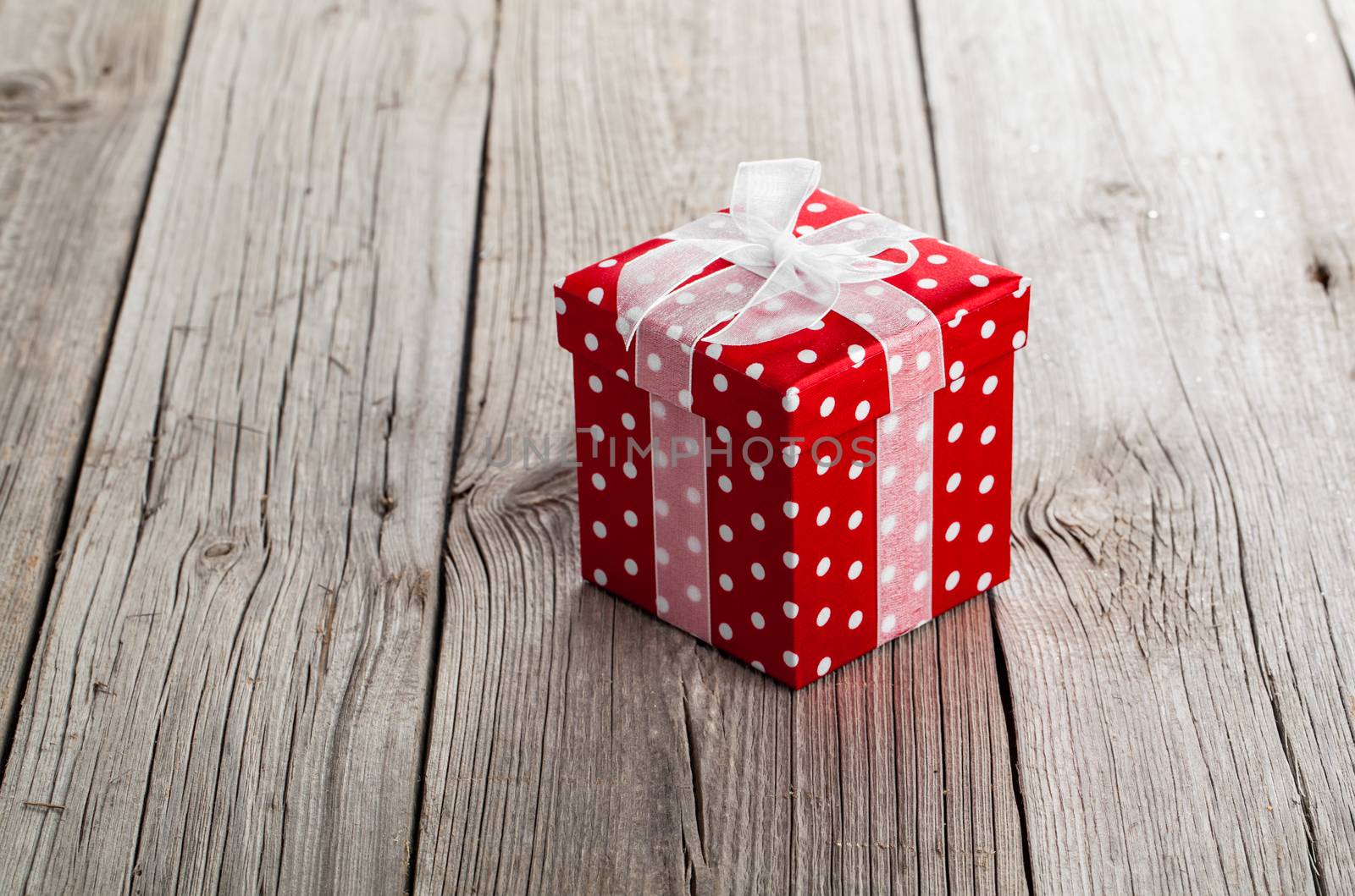 red gift box with bow on wood background