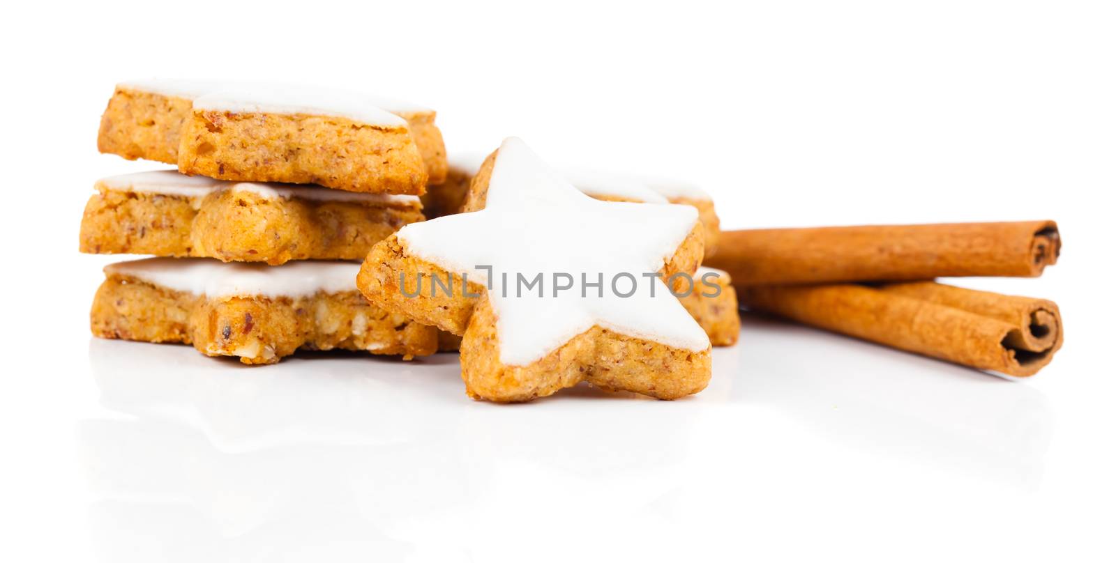star shaped cinnamon biscuit and cinnamon sticks on white background