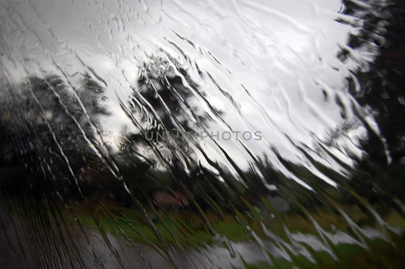 Heavy rain is falling under the window glass