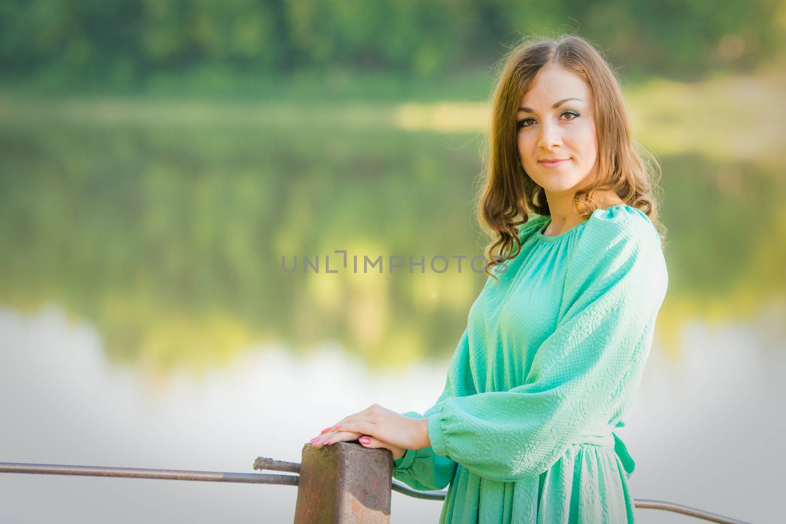The young beautiful girl walks on an old bridge in the warm autumn weather