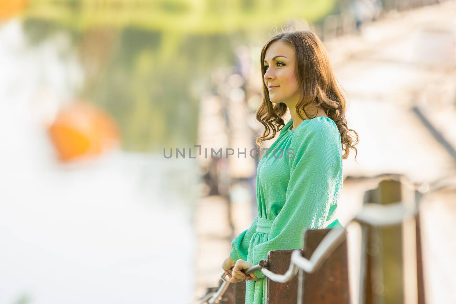 The young beautiful girl walks on an old bridge in the warm autumn weather