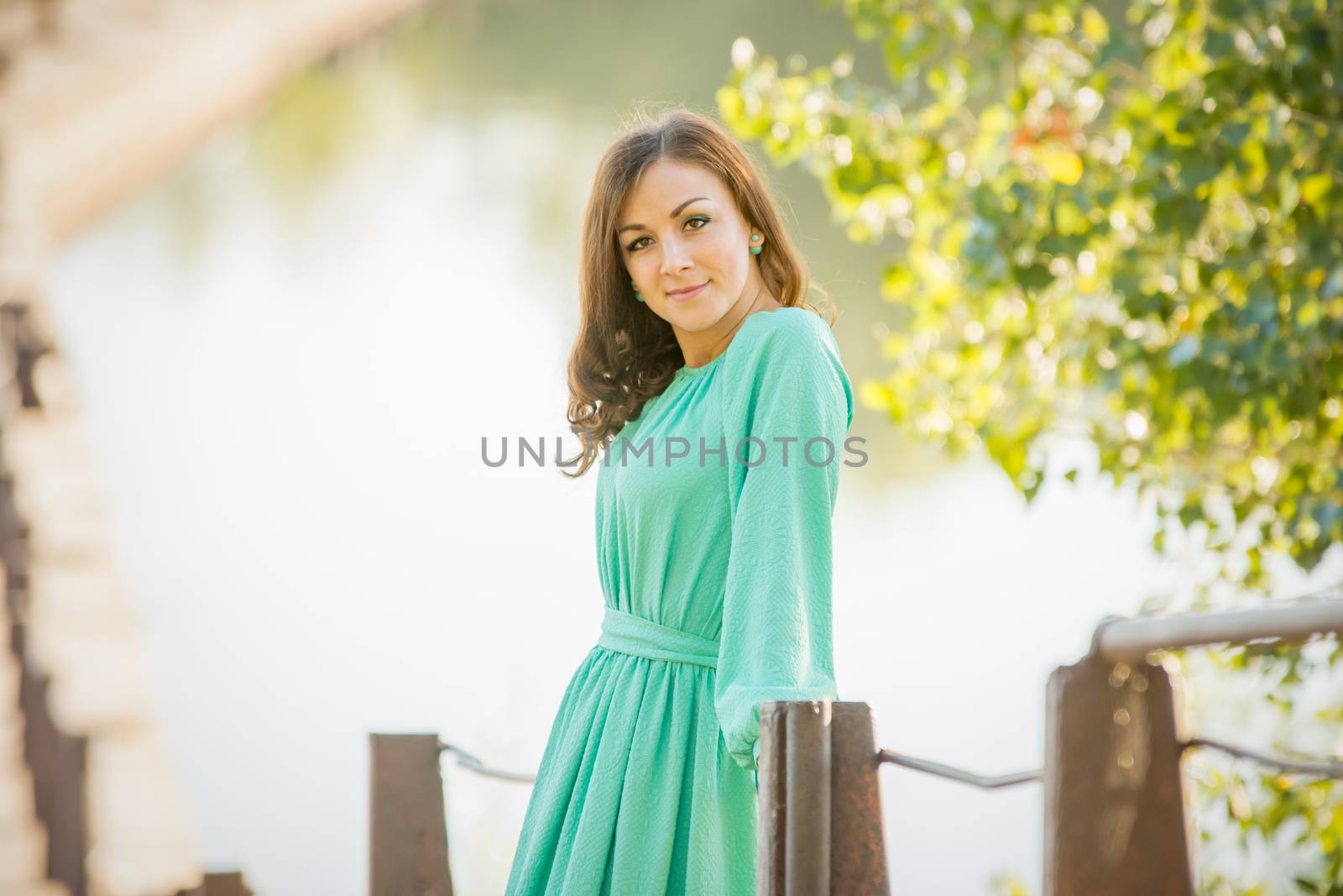 The young beautiful girl walks on an old bridge in the warm autumn weather