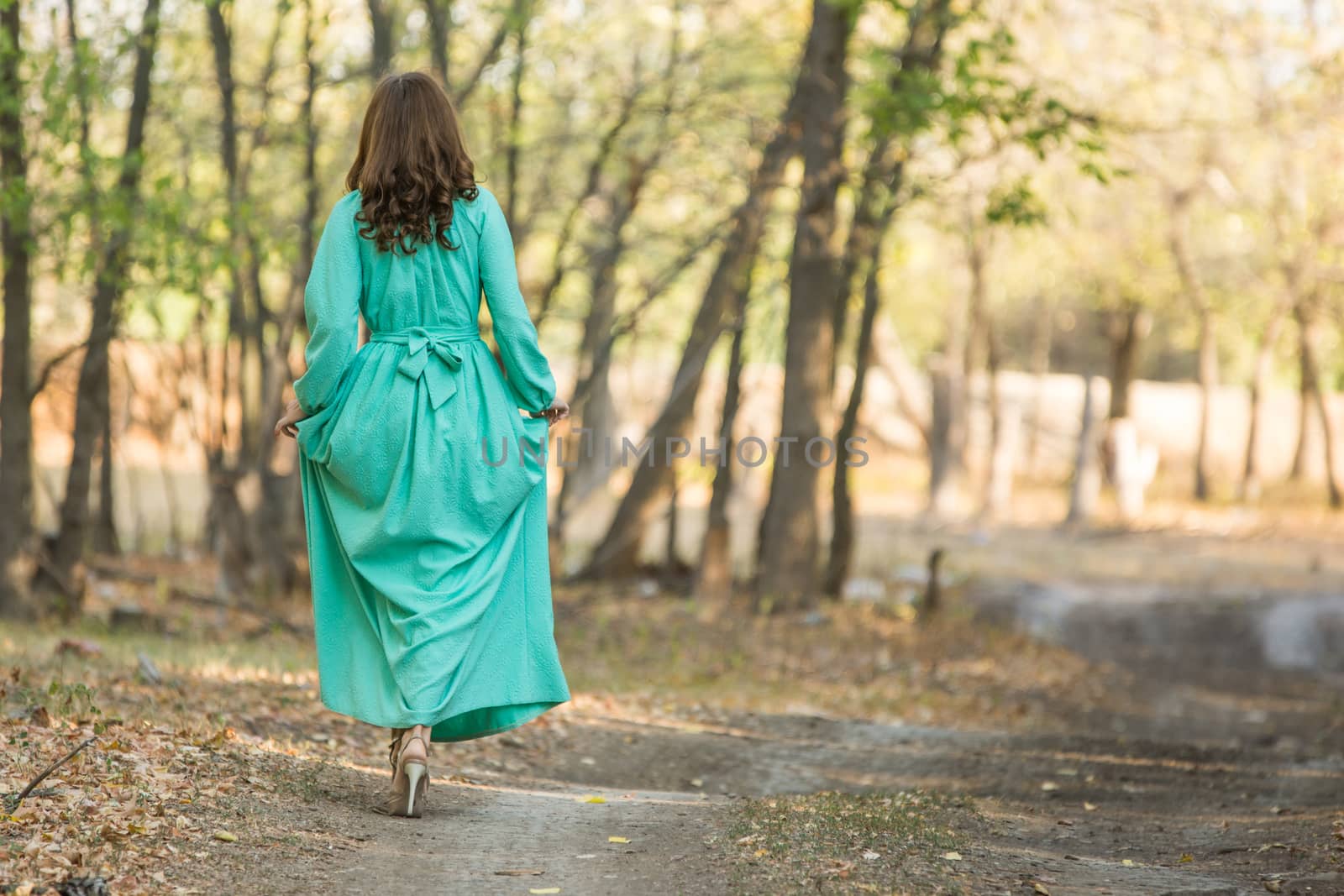Young beautiful girl in a long dress walking in the woods on a warm summer day