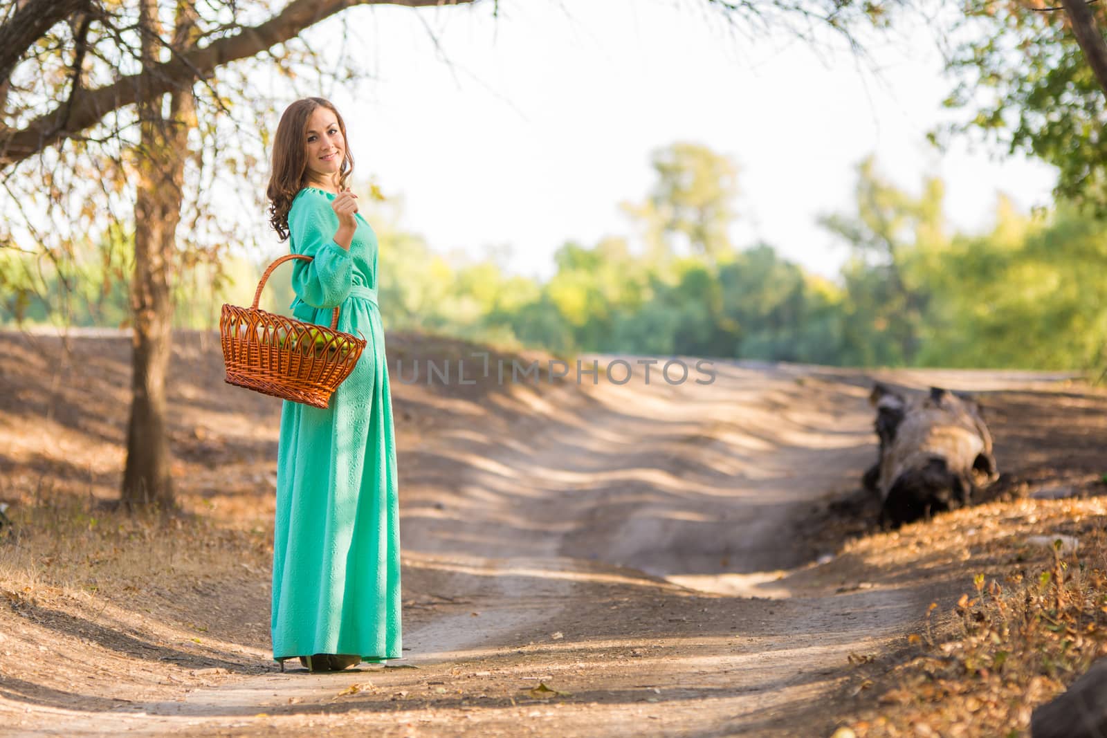 Young beautiful girl in a long dress walking in the woods on a warm summer day