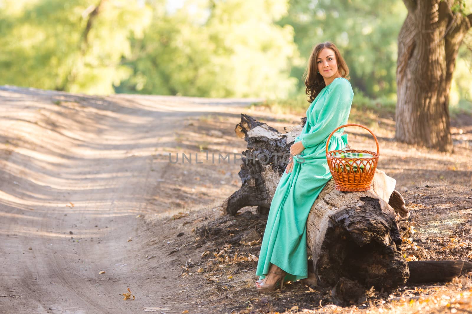 Young beautiful girl in a long dress walking in the woods on a warm summer day