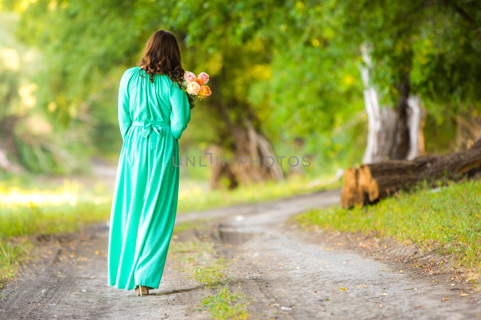 Young beautiful girl in a long dress walking in the woods on a warm summer day