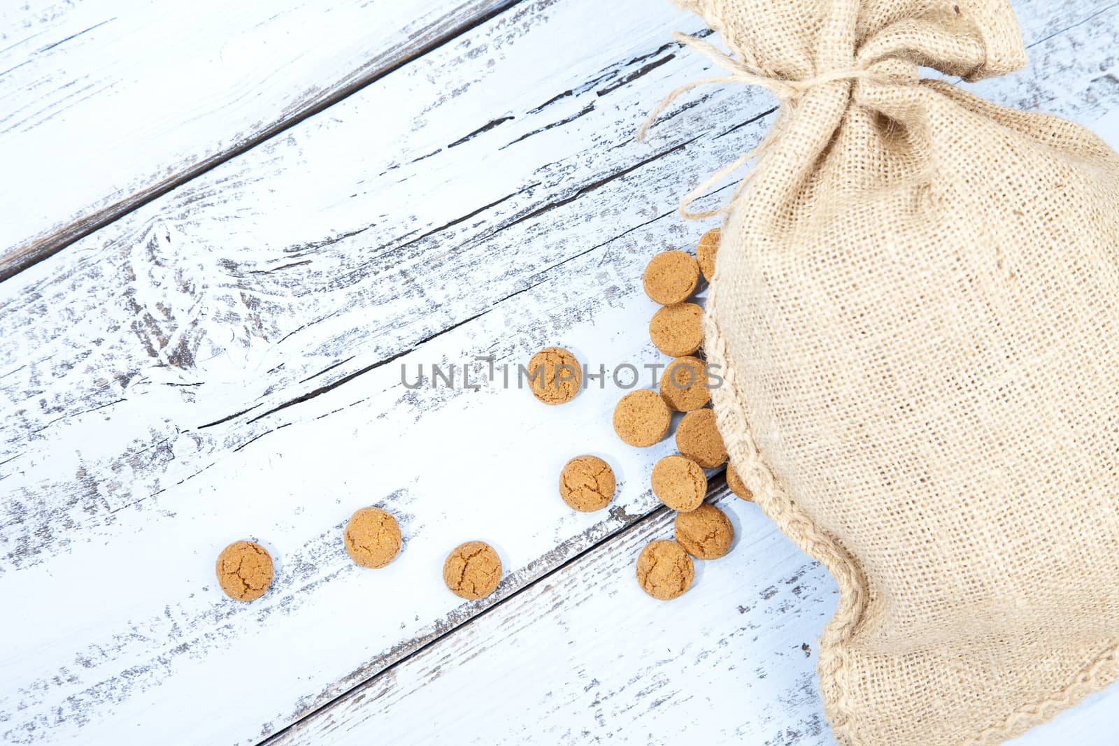 Dutch candy pepernoot with jute bag on white blue wooden background