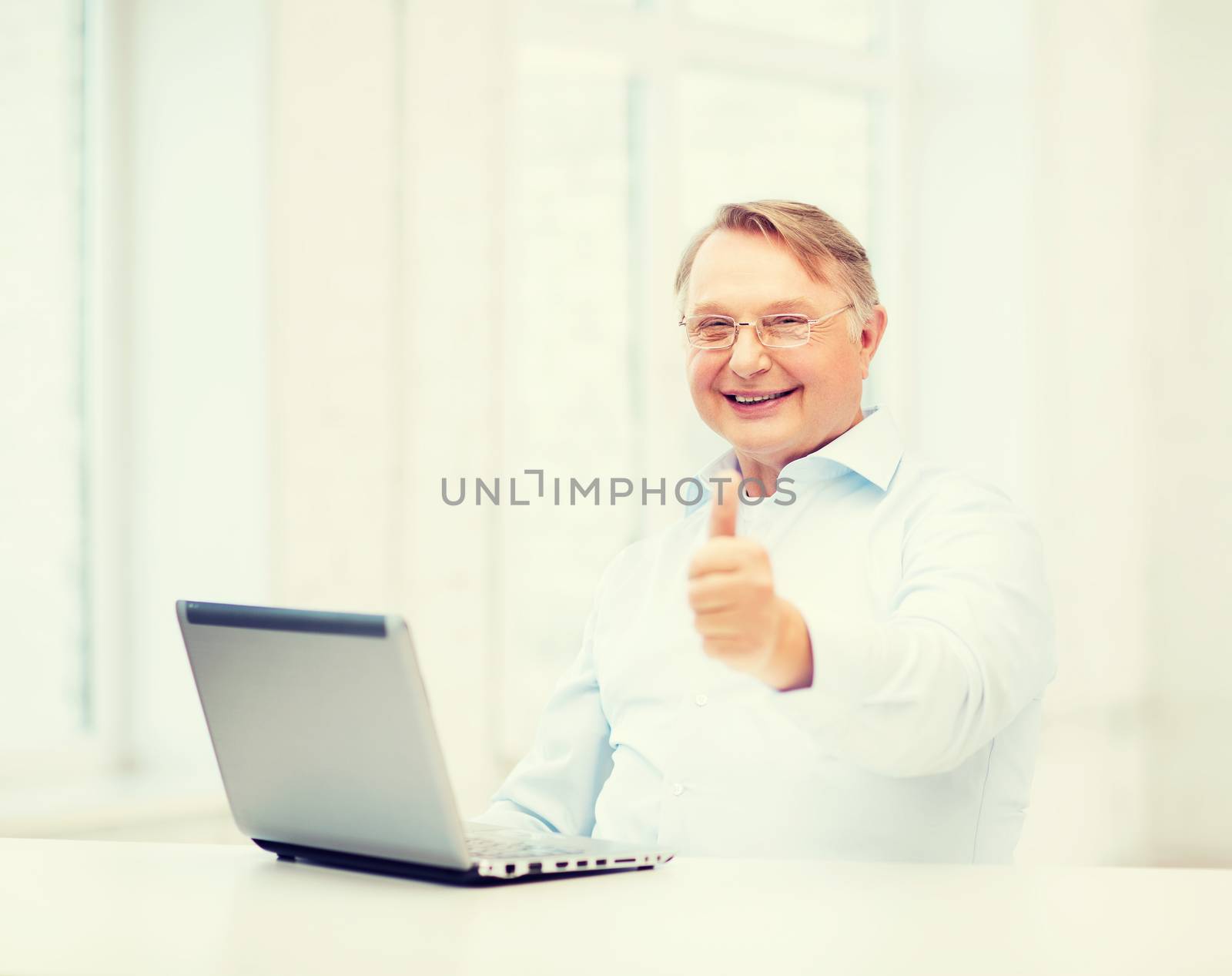 technology, oldness and lifestyle concept - old man in eyeglasses with laptop computer at home showing thumbs up
