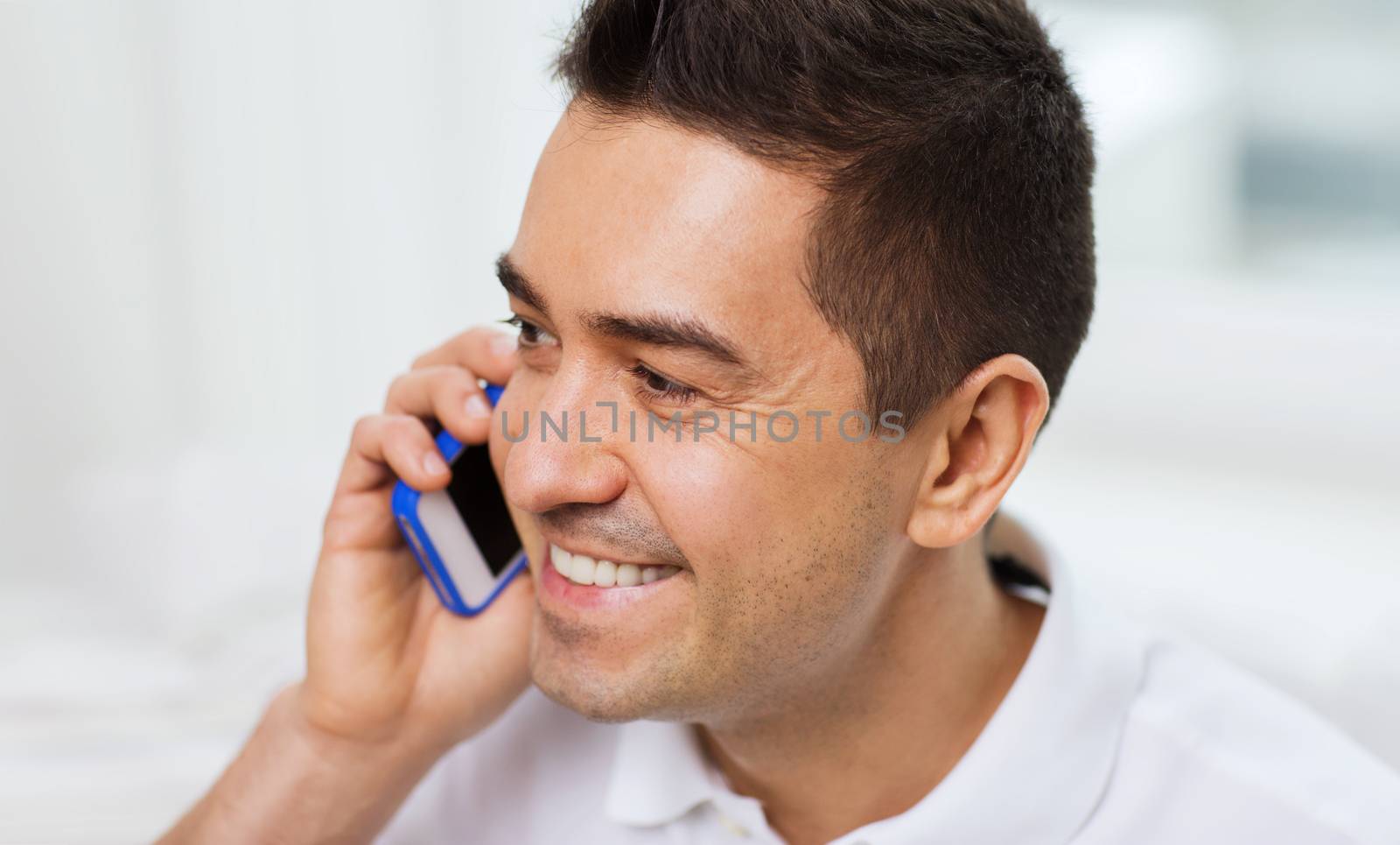 happy man calling on smartphone at home by dolgachov