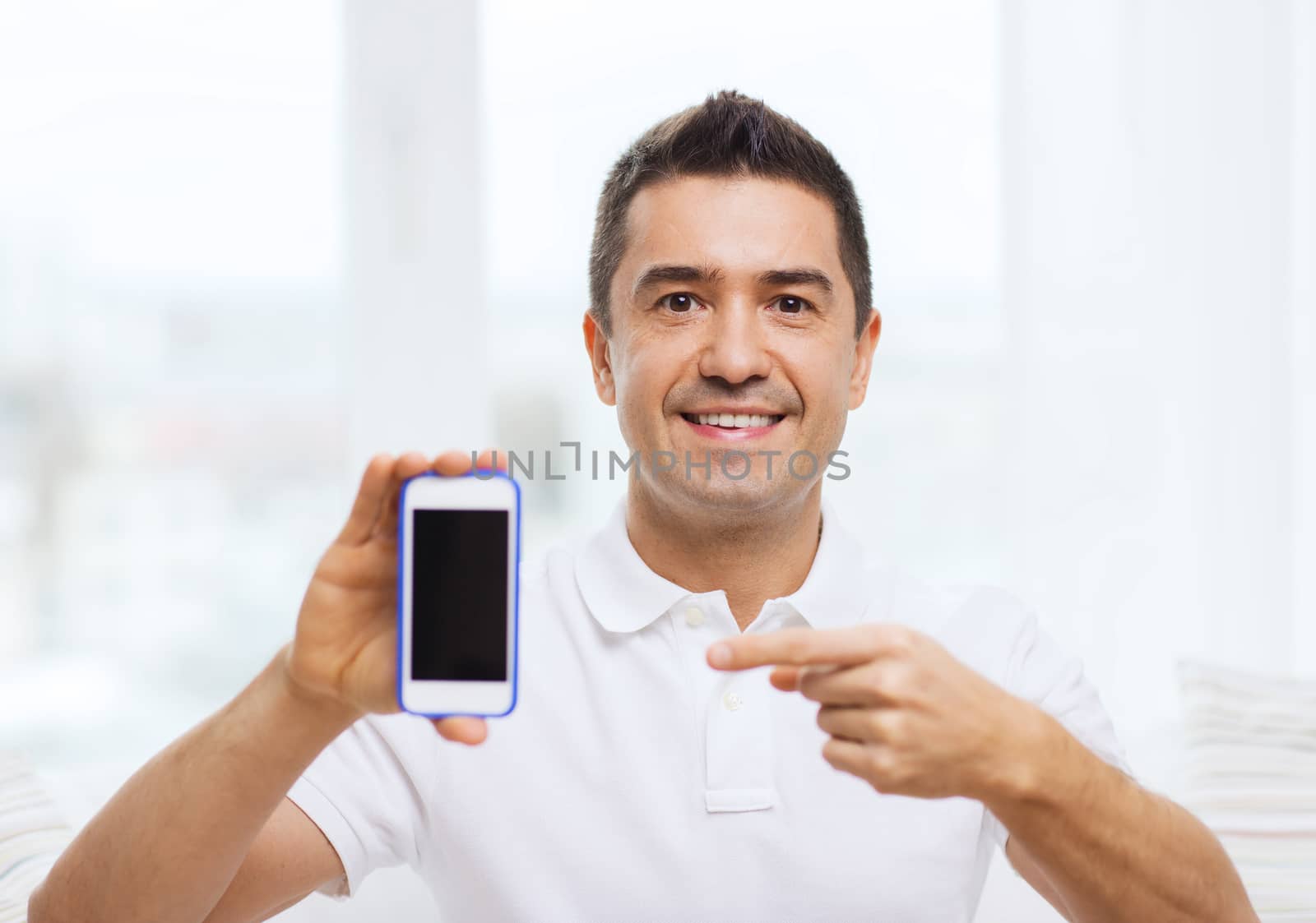 technology, people, lifestyle and communication concept - happy man showing smartphone black blank screen at home