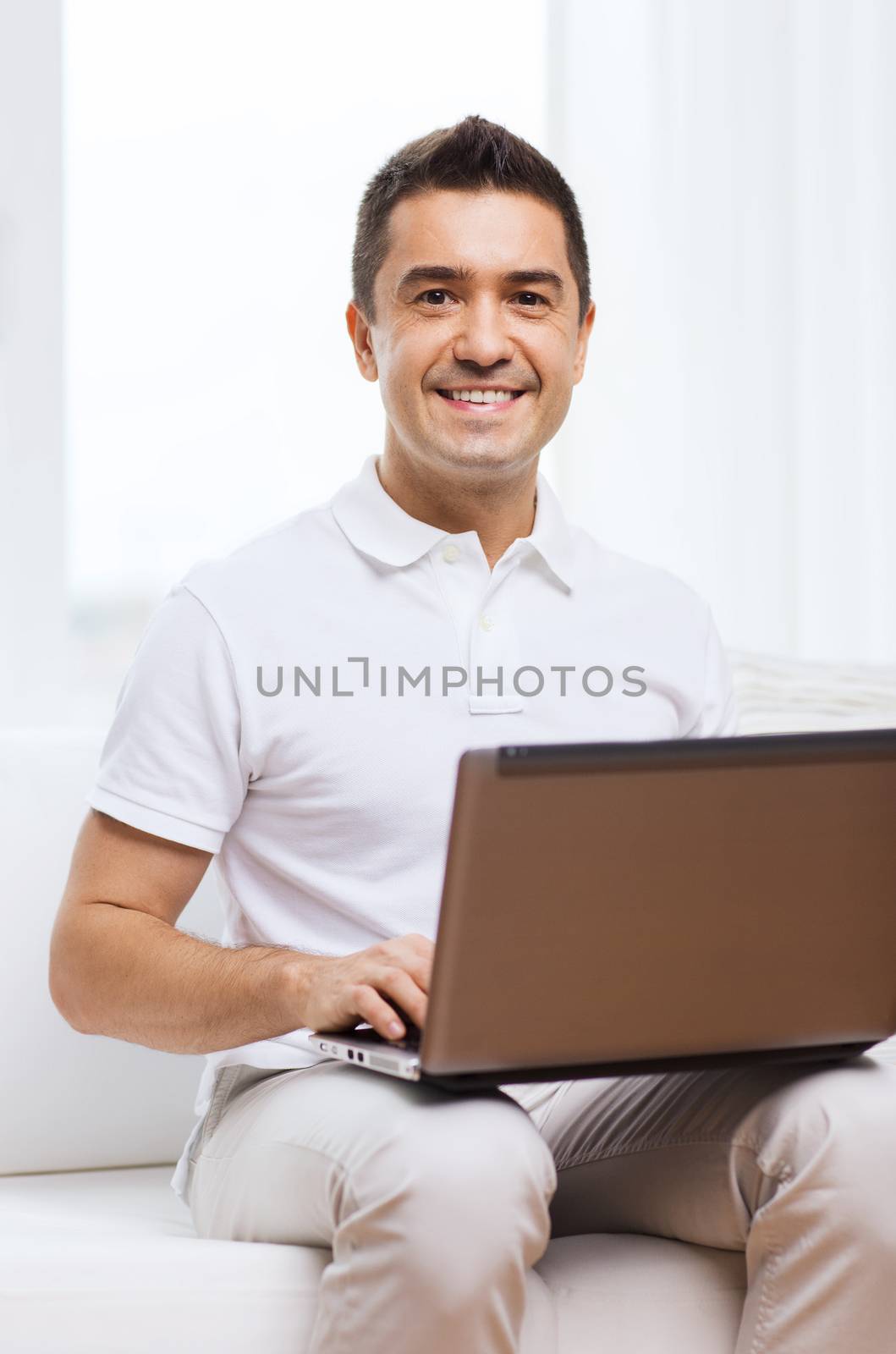 happy man working with laptop computer at home by dolgachov