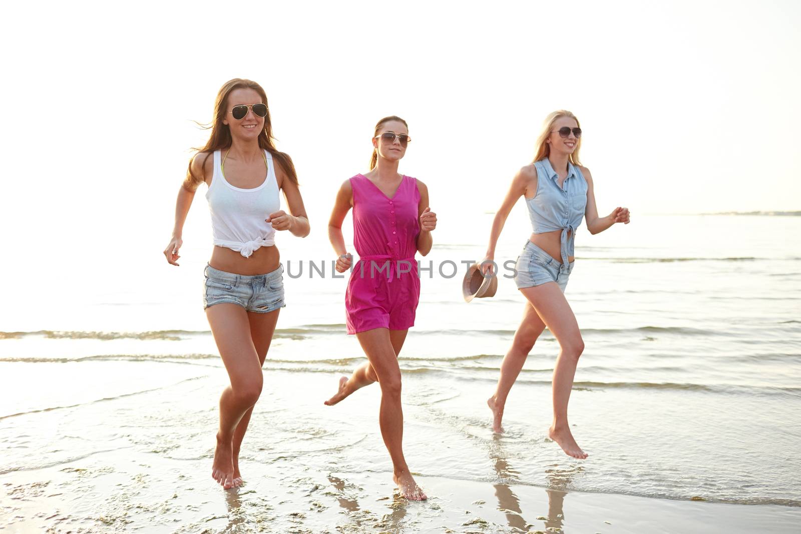 group of smiling women running on beach by dolgachov