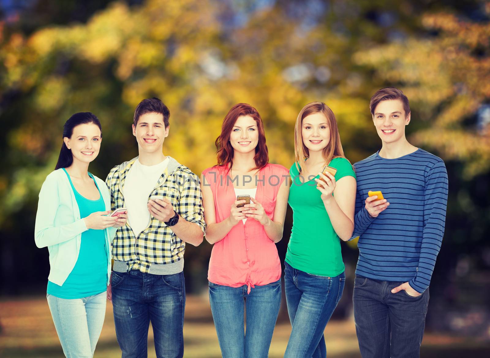 smiling students with smartphones by dolgachov