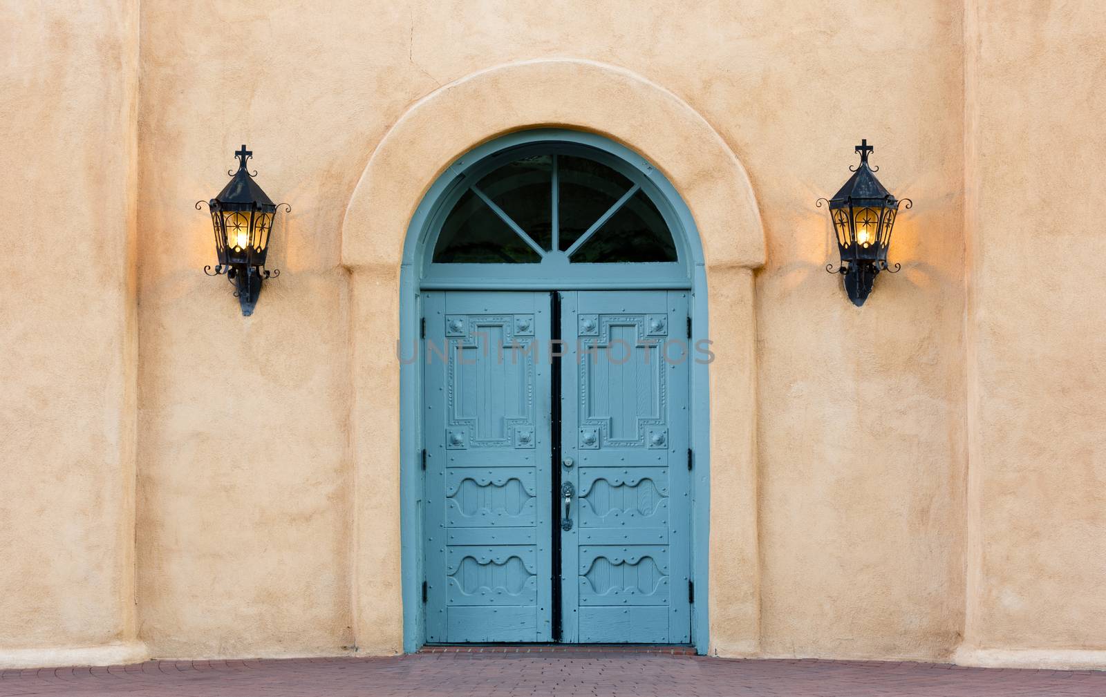 Blue, double doors of San Felipe de Neri church in Old Town, Albuquerque, New Mexico.  Iron lanterns on sides of adobe wall.  Building constructed in 1793 and listed on the National Register of Historic Places, America's official list of nation's historic places worthy of preservation.