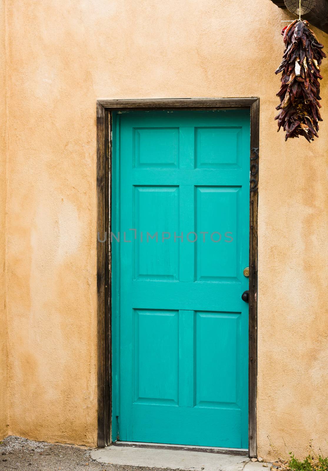 Old Pueblo Spanish style building with adobe walls enhanced by blue door with hanging red peppers.  Location is Old Town district in Albuquerque, New Mexico, in America's Southwest region.  Vertical image with copy space. 
