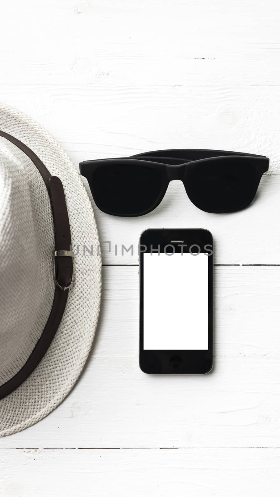 hat sunglasses and smart phone on white table