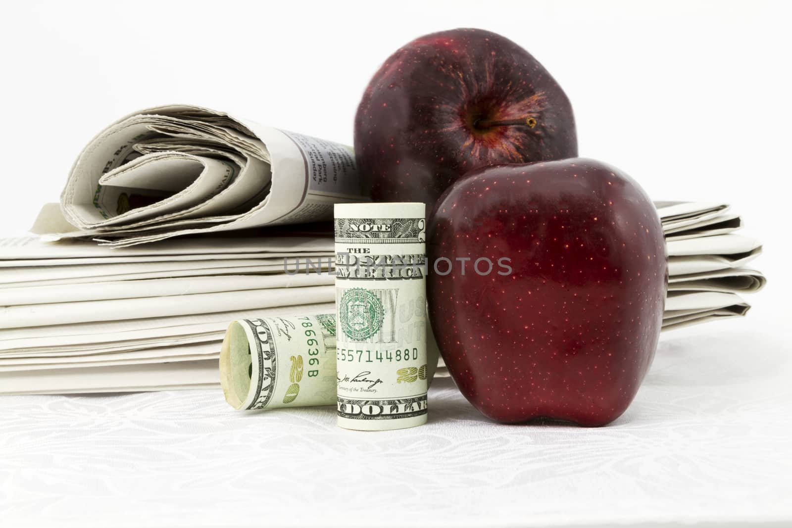 Two apples and American currency placed with stack of newspapers reflect news and information on education bonds and finances.  