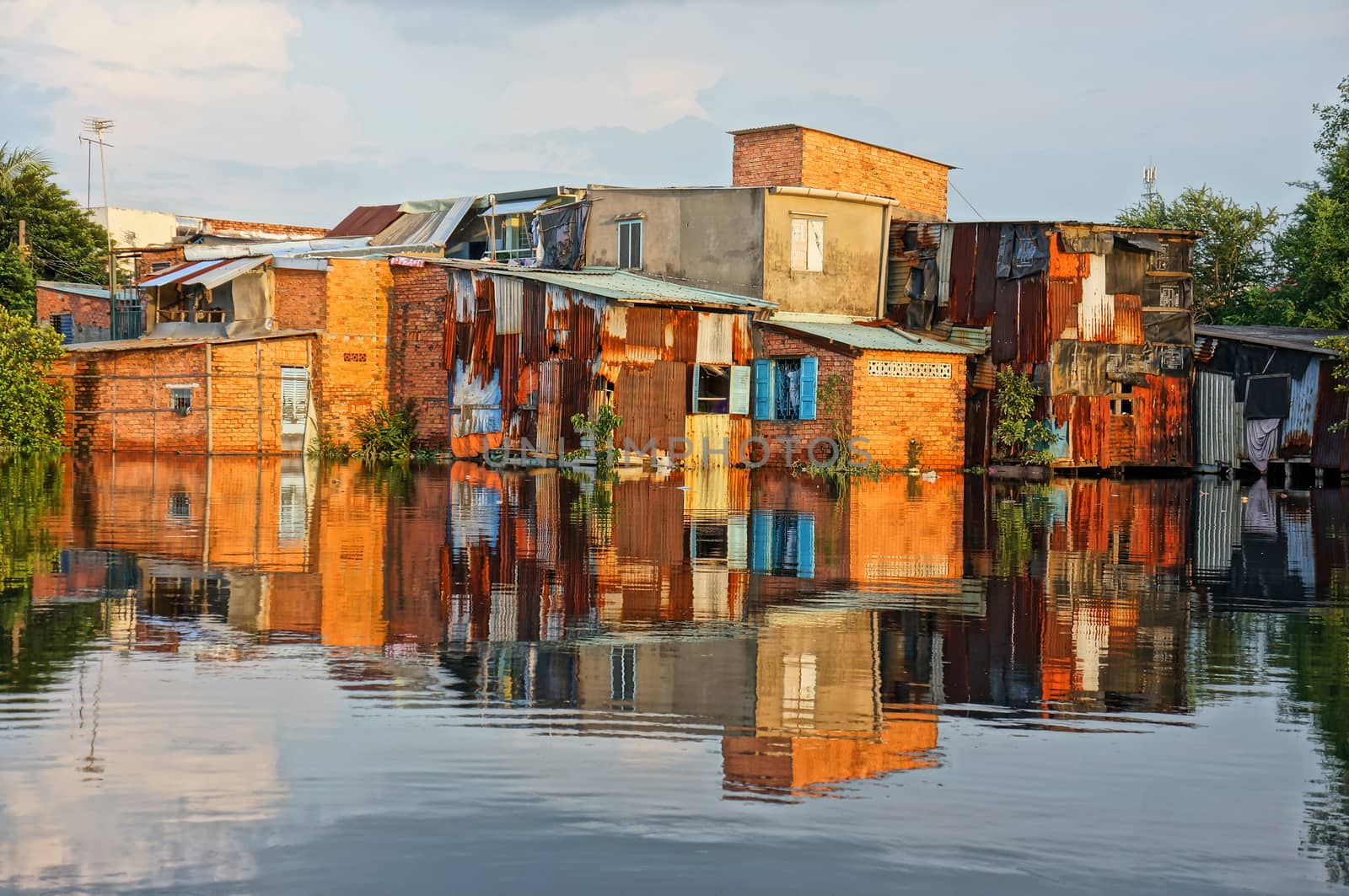 HO CHI MINH CITY, VIET NAM- OCT 10: Group of riverside downgrade house with red brick wall, poor residence near canal, danger and  unsafe life in climate change situation, Vietnam, Oct 10, 2014