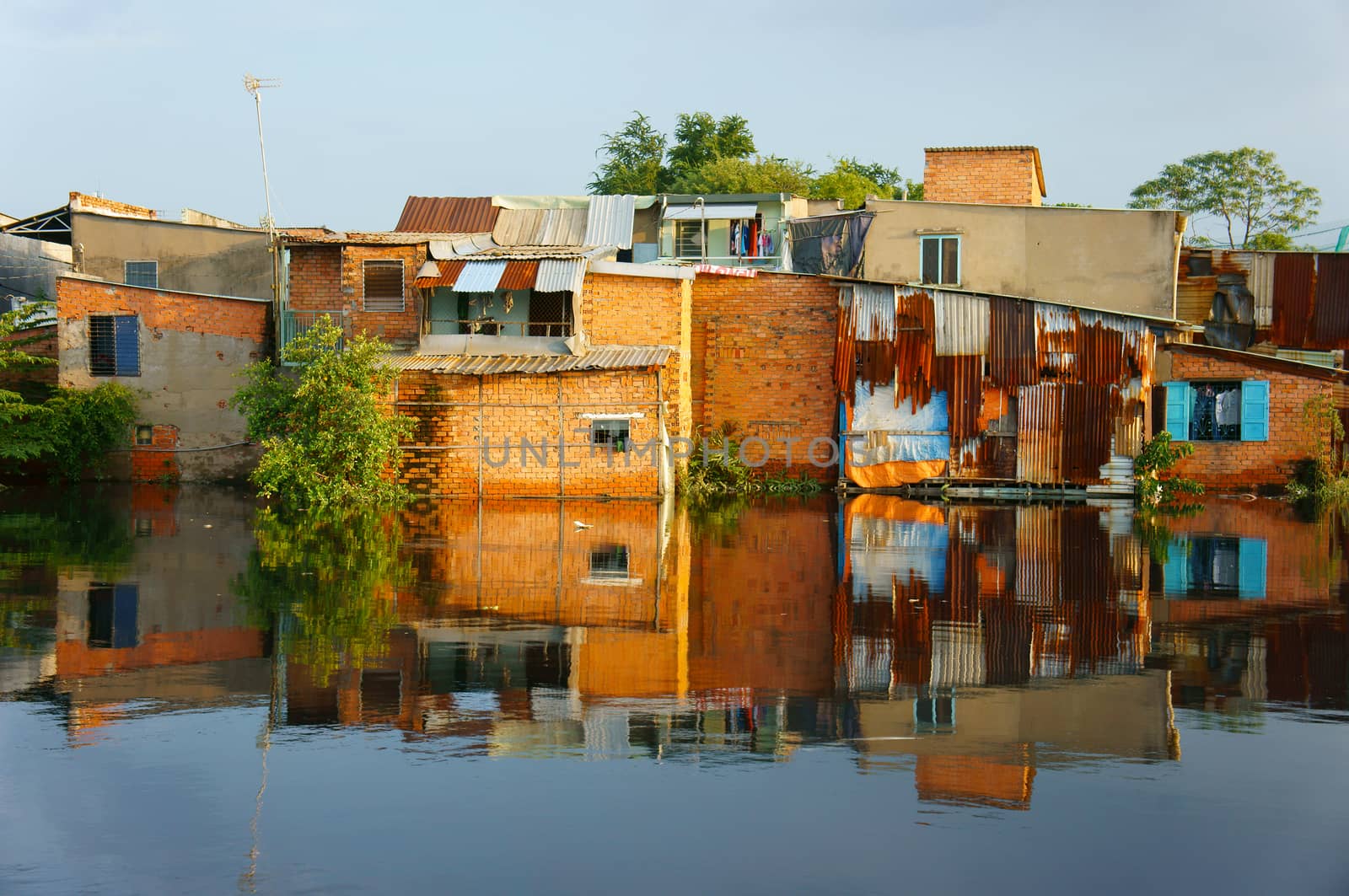 HO CHI MINH CITY, VIET NAM- OCT 10: Group of riverside downgrade house with red brick wall, poor residence near canal, danger and  unsafe life in climate change situation, Vietnam, Oct 10, 2014