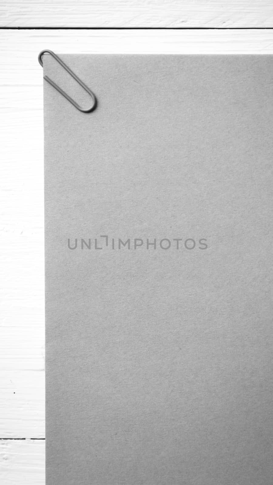 brown paper with green paper clip over white table black and white color
