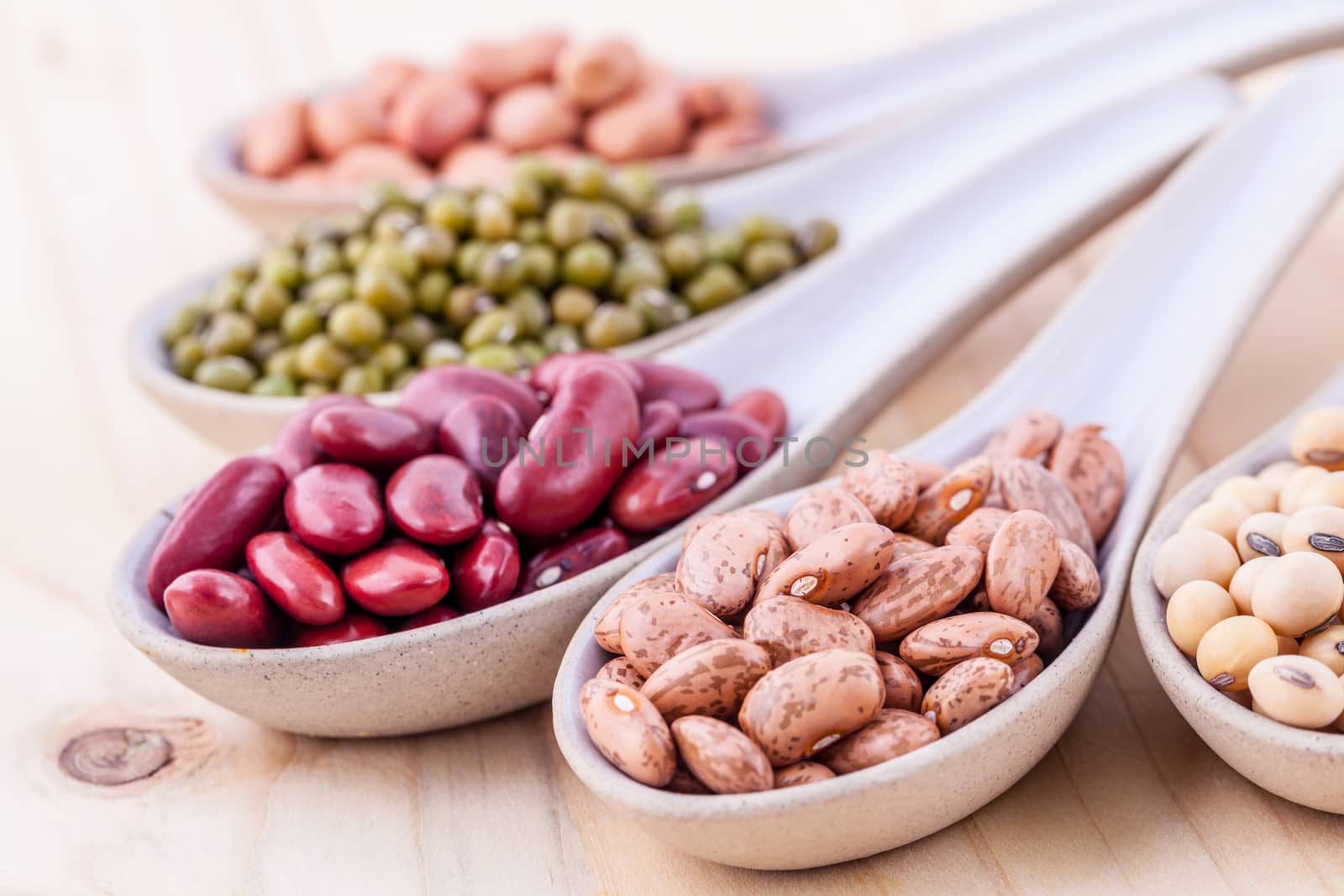 Assortment of beans and lentils in wooden spoon on wooden background. mung bean, groundnut, soybean, red kidney bean , black bean ,red bean and brown pinto beans .