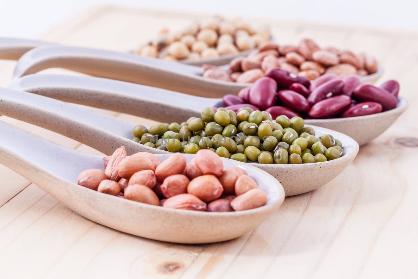 Assortment of beans and lentils in wooden spoon on wooden background. mung bean, groundnut, soybean, red kidney bean , black bean ,red bean and brown pinto beans .