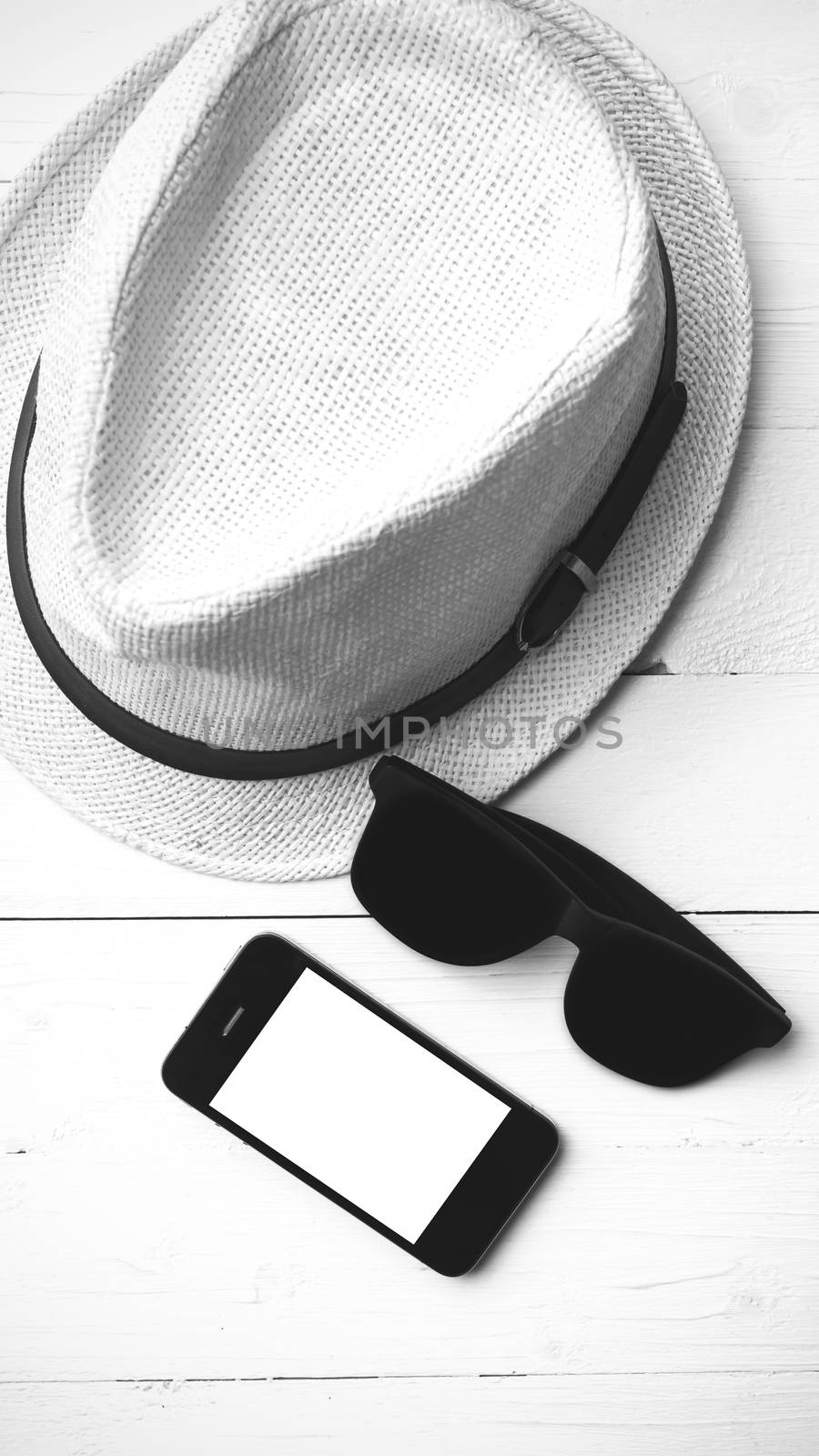 hat sunglasses and smart phone on white table black and white color