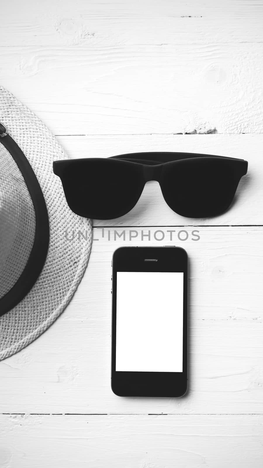 hat sunglasses and smart phone on white table black and white color