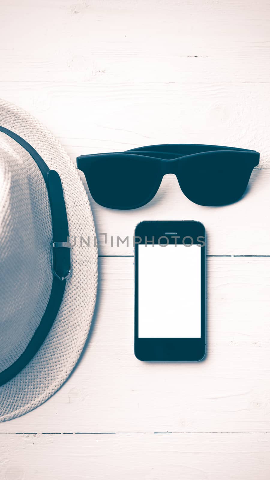 hat sunglasses and smart phone on white table vintage style