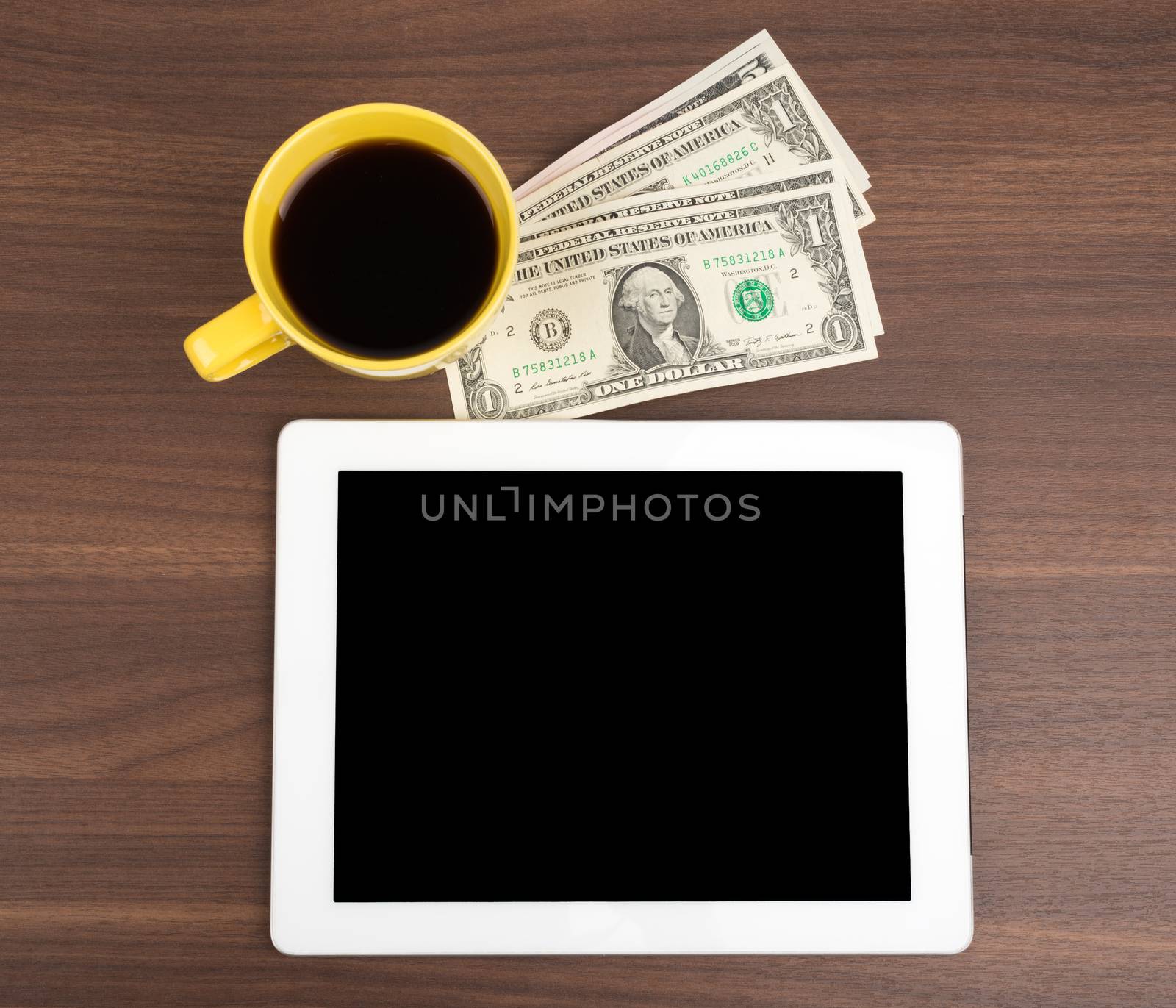 Tablet with coffee and money on wooden table