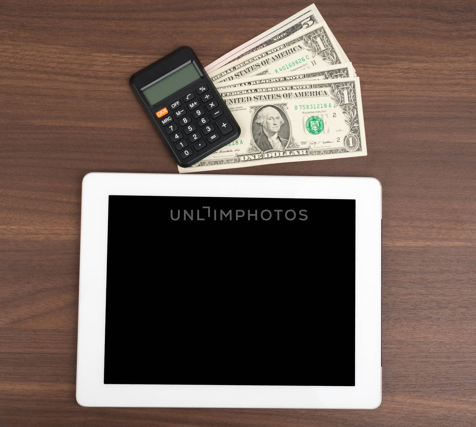 Tablet with money and calculator on wooden table