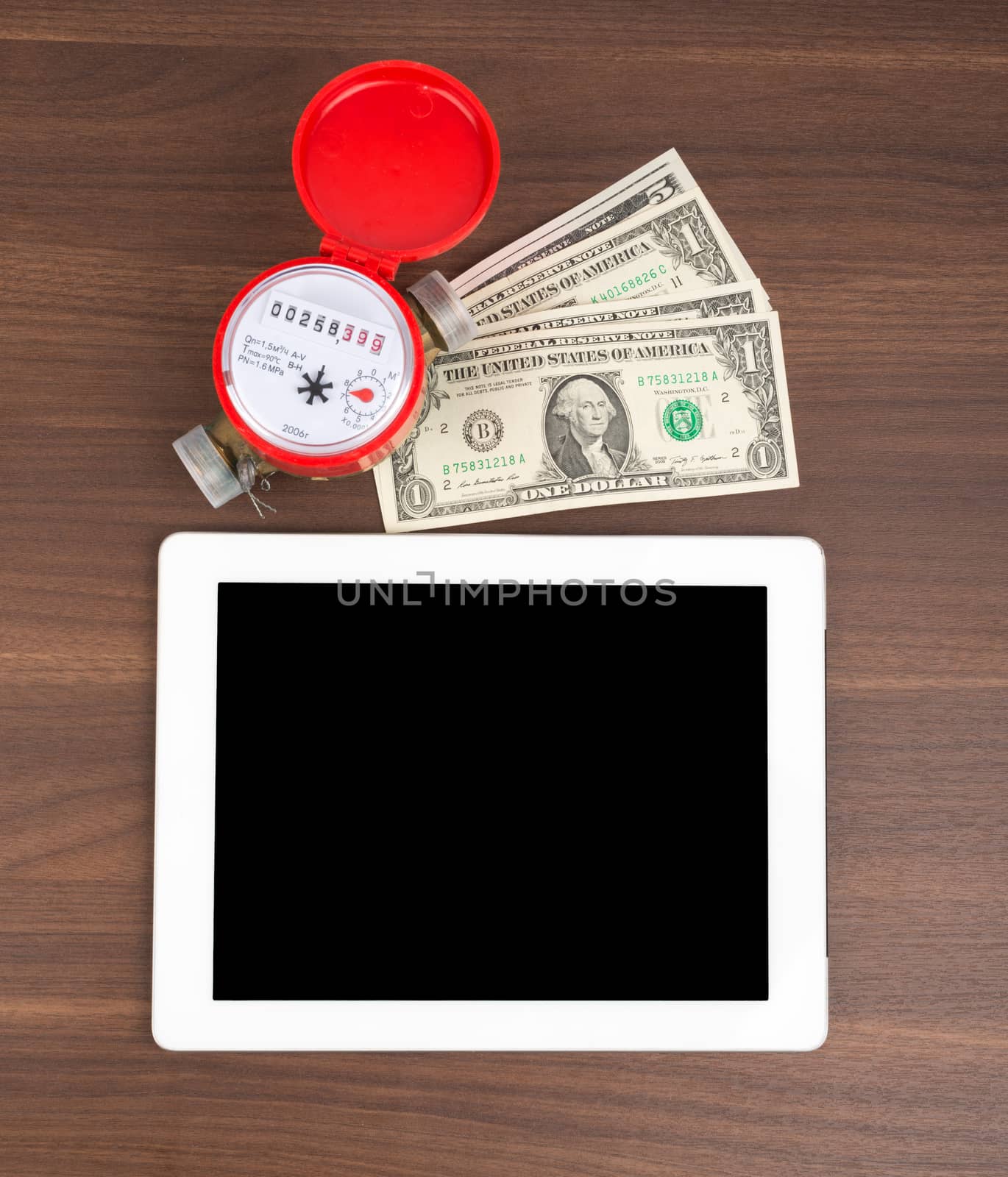 Tablet with money and water meter on wooden table