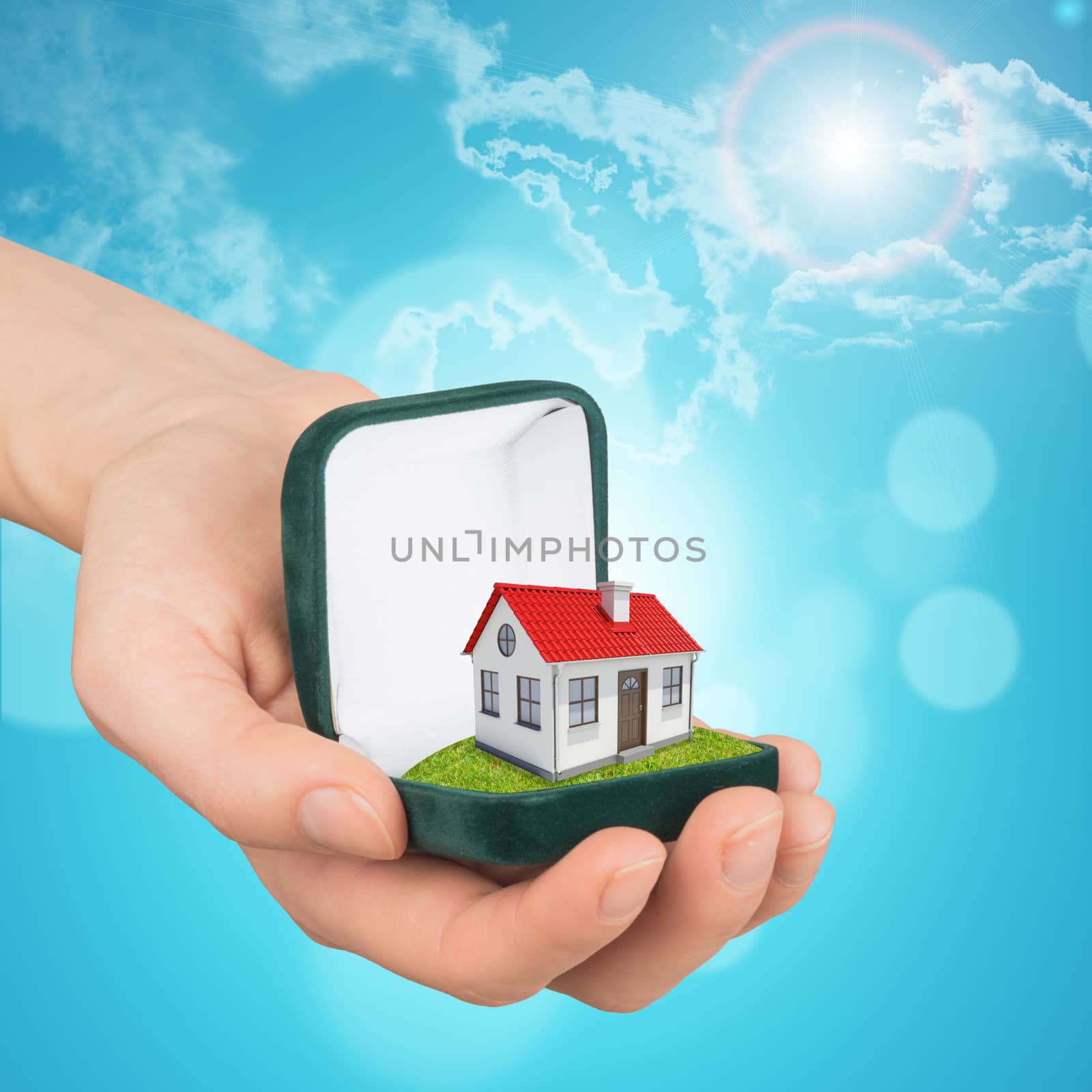 Empty ring box house in humans hand on blue sky background