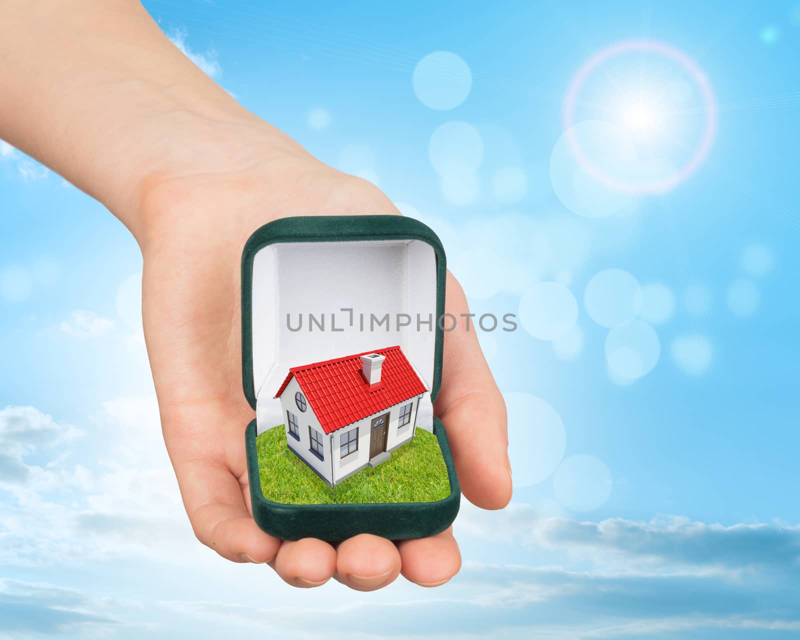 Empty ring box house in humans hand on blue sky background