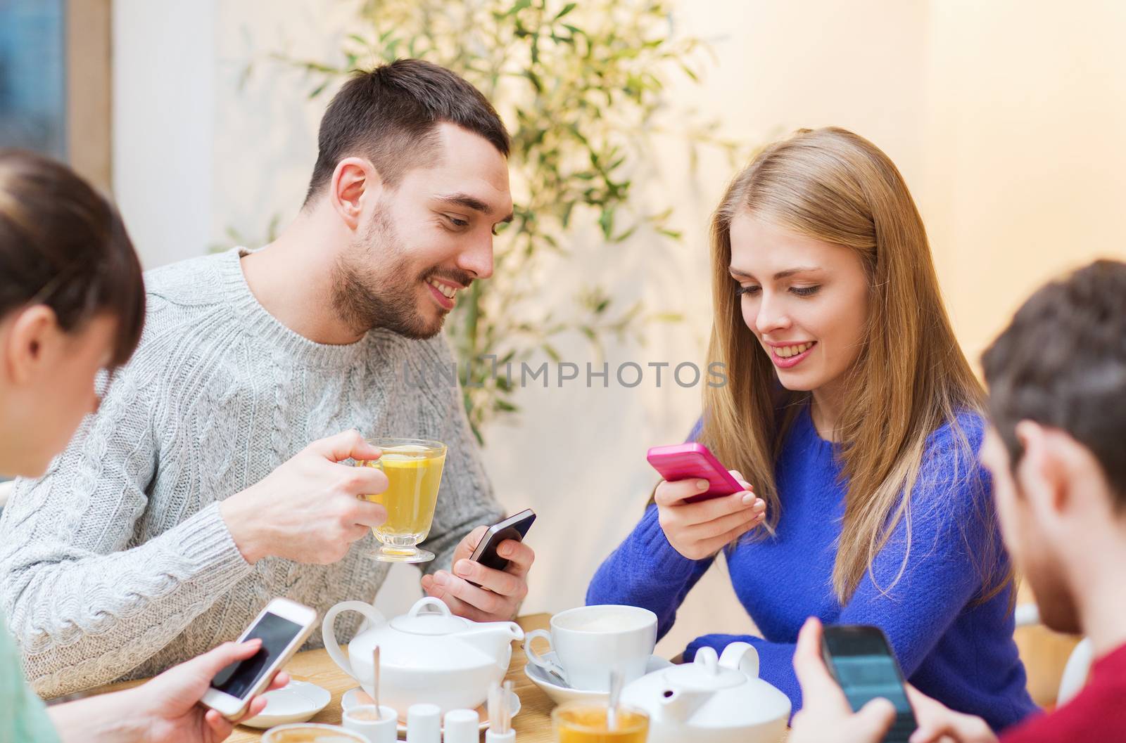 group of friends with smartphones meeting at cafe by dolgachov