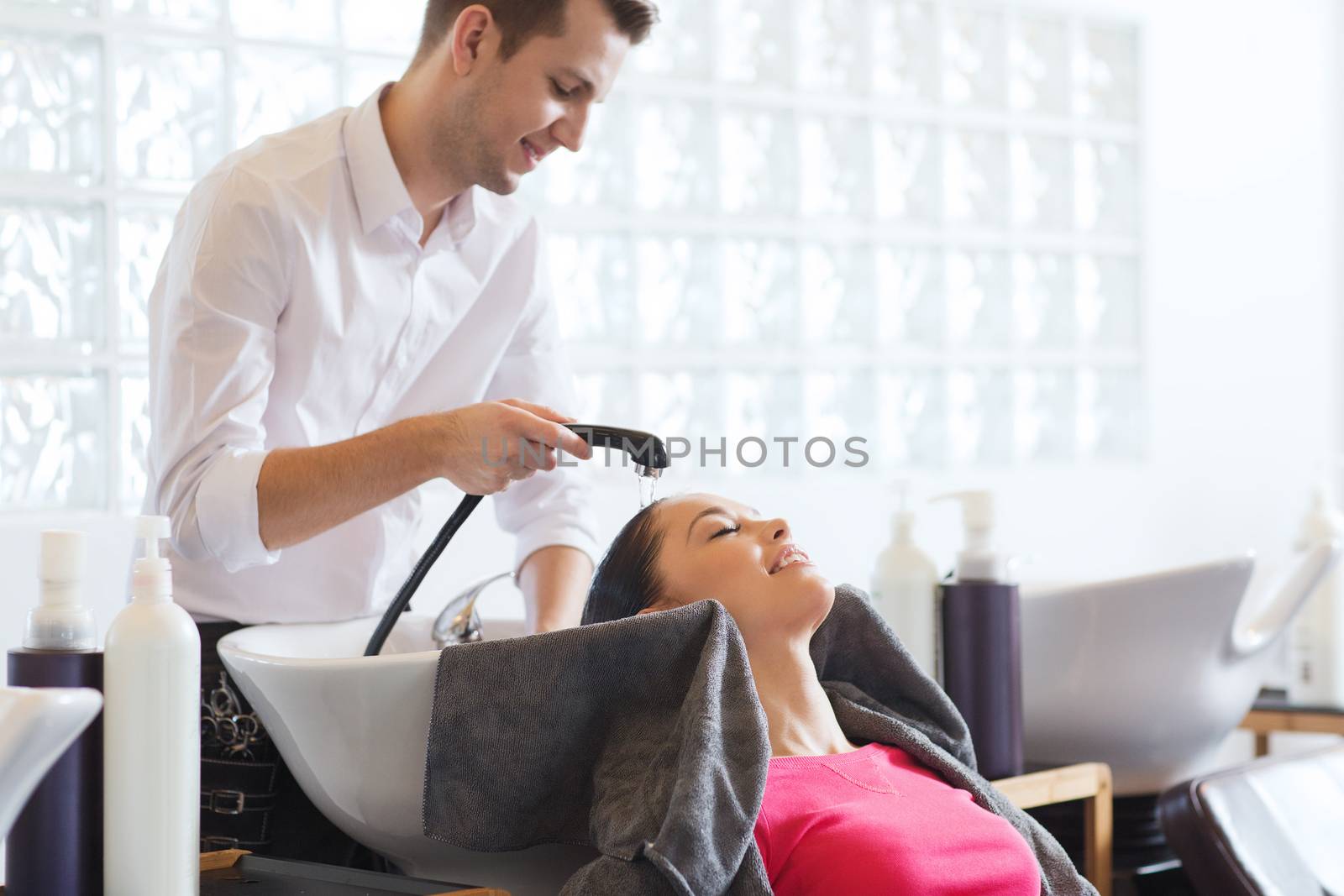 beauty and people concept - happy young woman with hairdresser washing head at hair salong