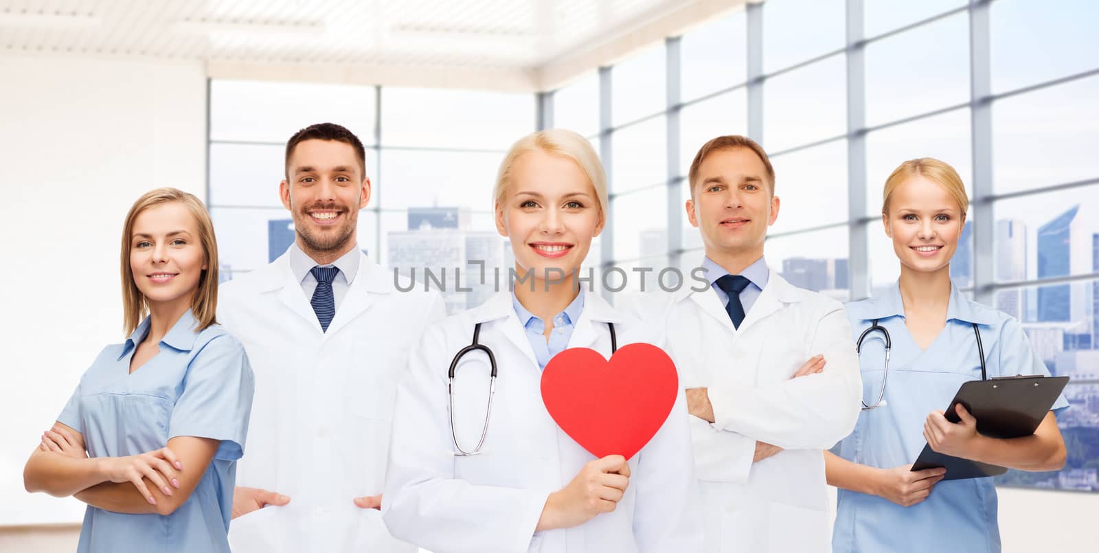 happy young doctors cardiologists with red heart by dolgachov