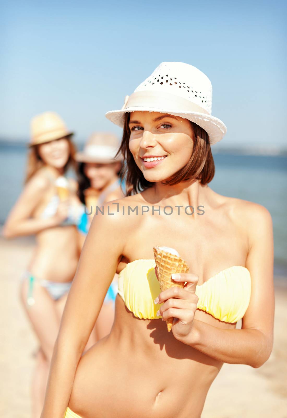 summer holidays and vacation - girl in bikini eating ice cream on the beach