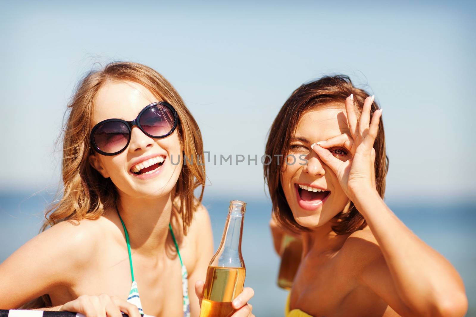 summer holidays and vacation - girls in bikinis with drinks on the beach chairs