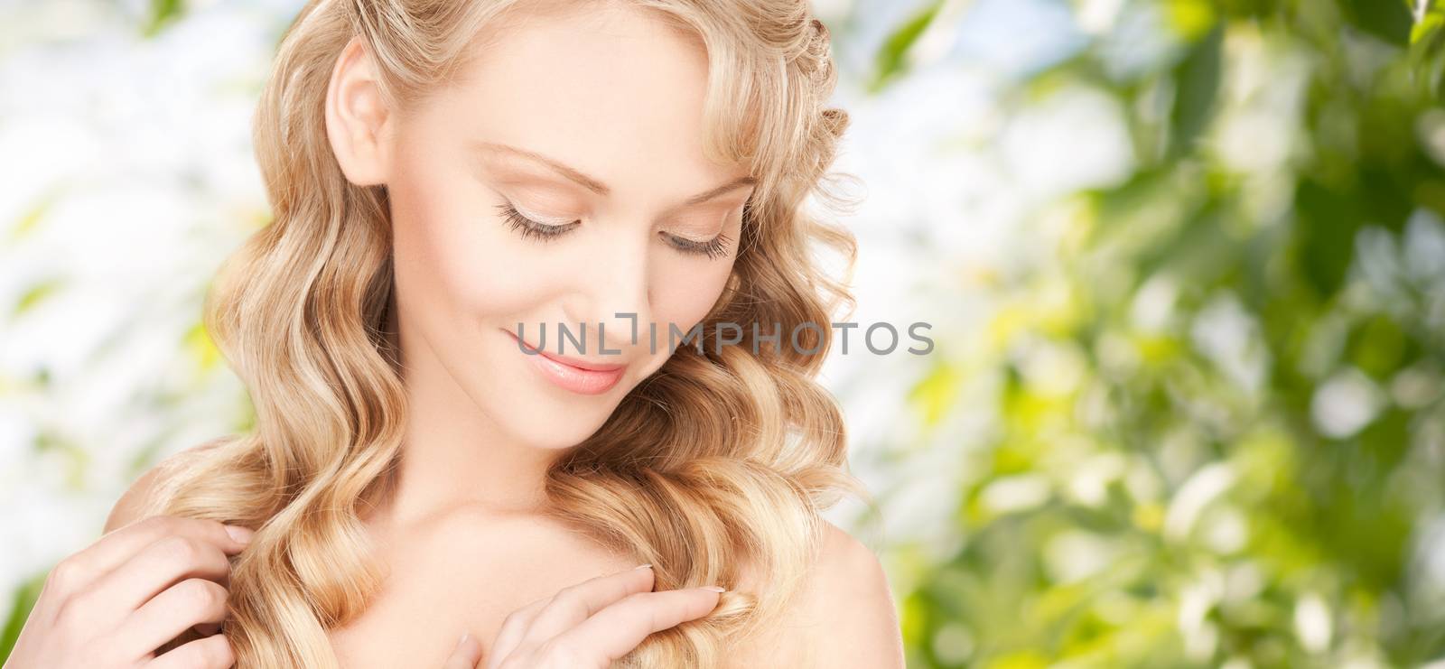 beauty, people, hair care and health concept - beautiful young woman face with long wavy hair over green background