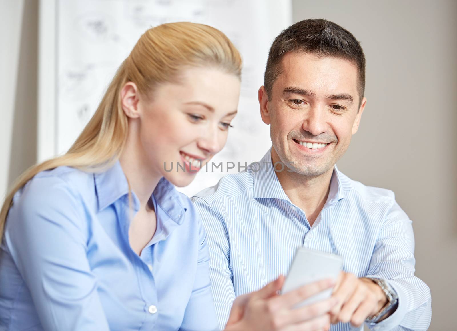 smiling businesspeople with smartphones in office by dolgachov