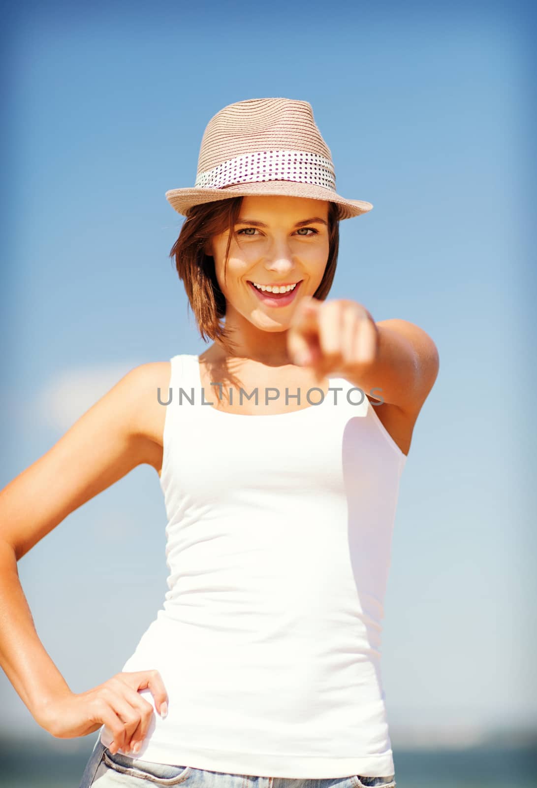 summer holidays and vacation - girl in hat pointing at you on the beach