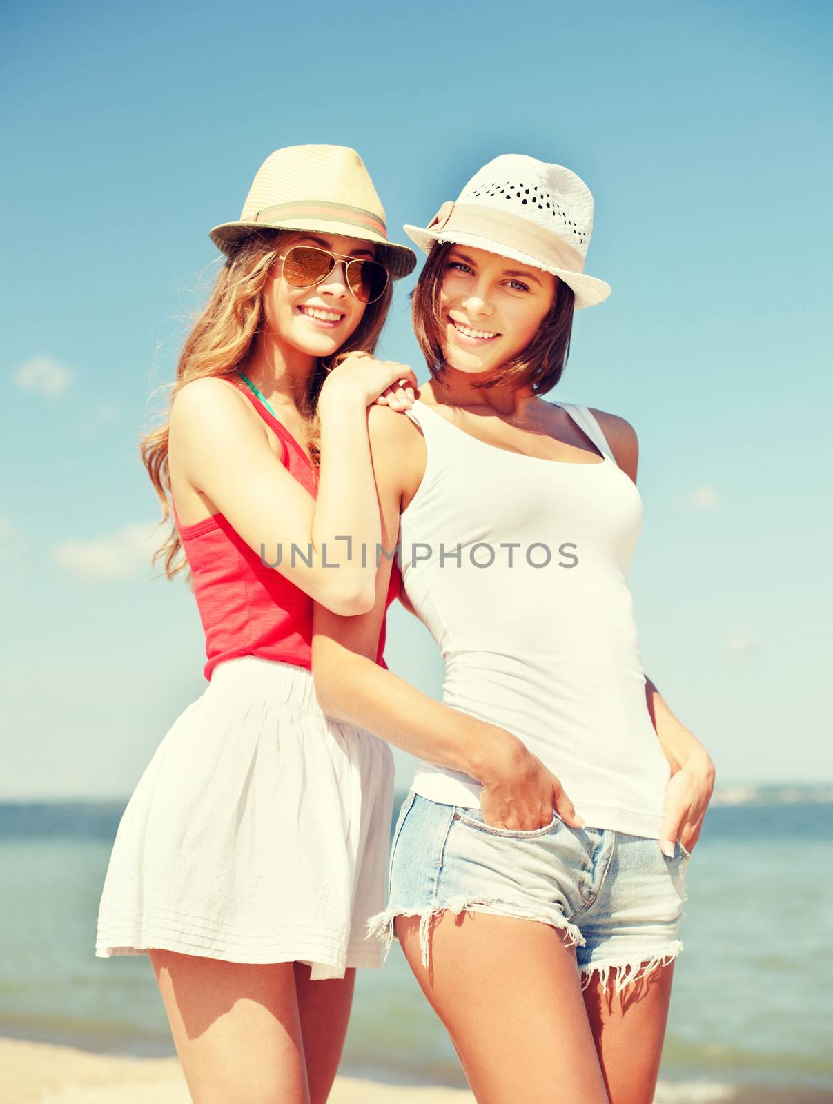 summer holidays and vacation concept - girls in hats on the beach