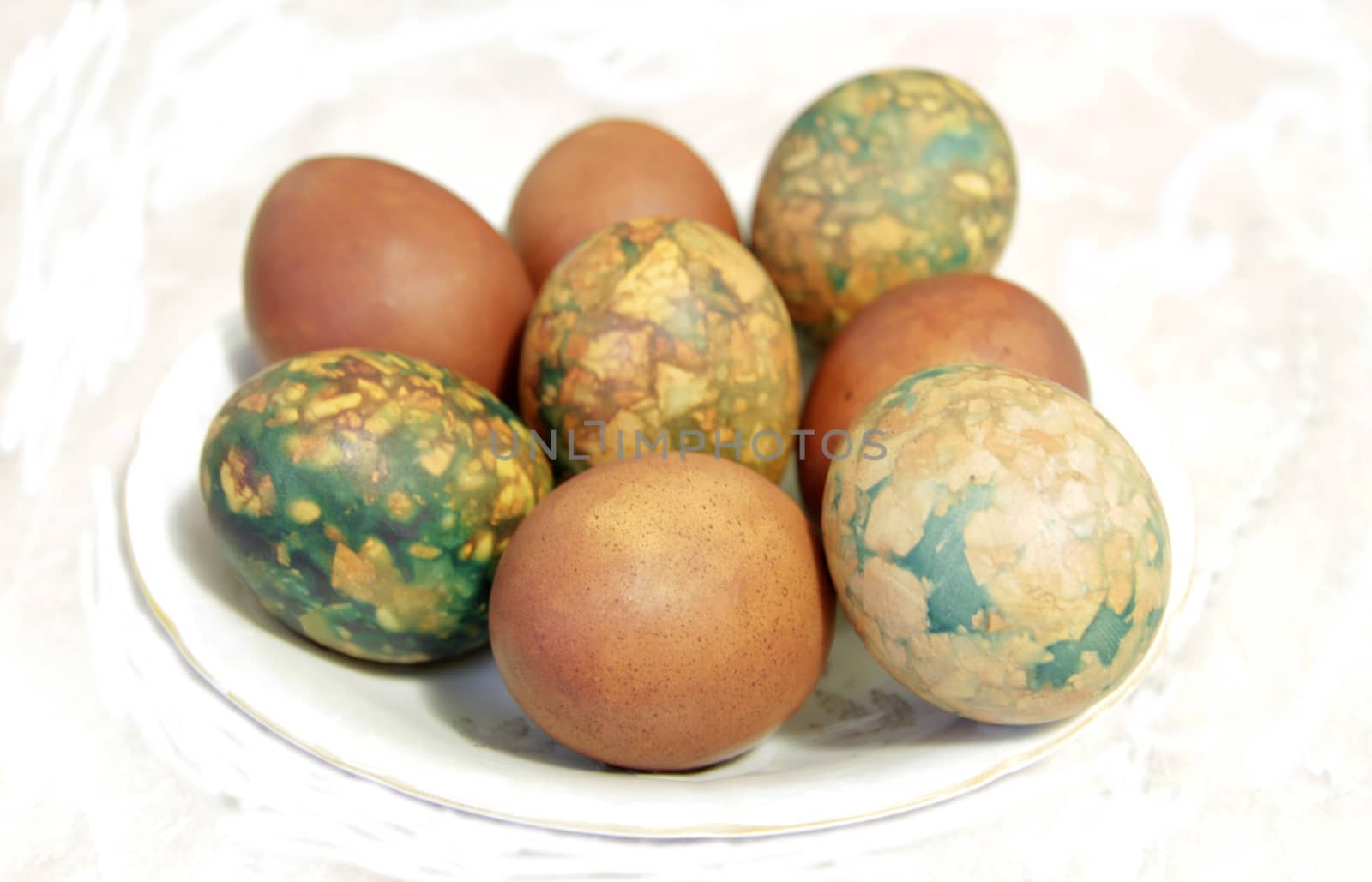 Colorful Easter eggs on white plate placed by heap