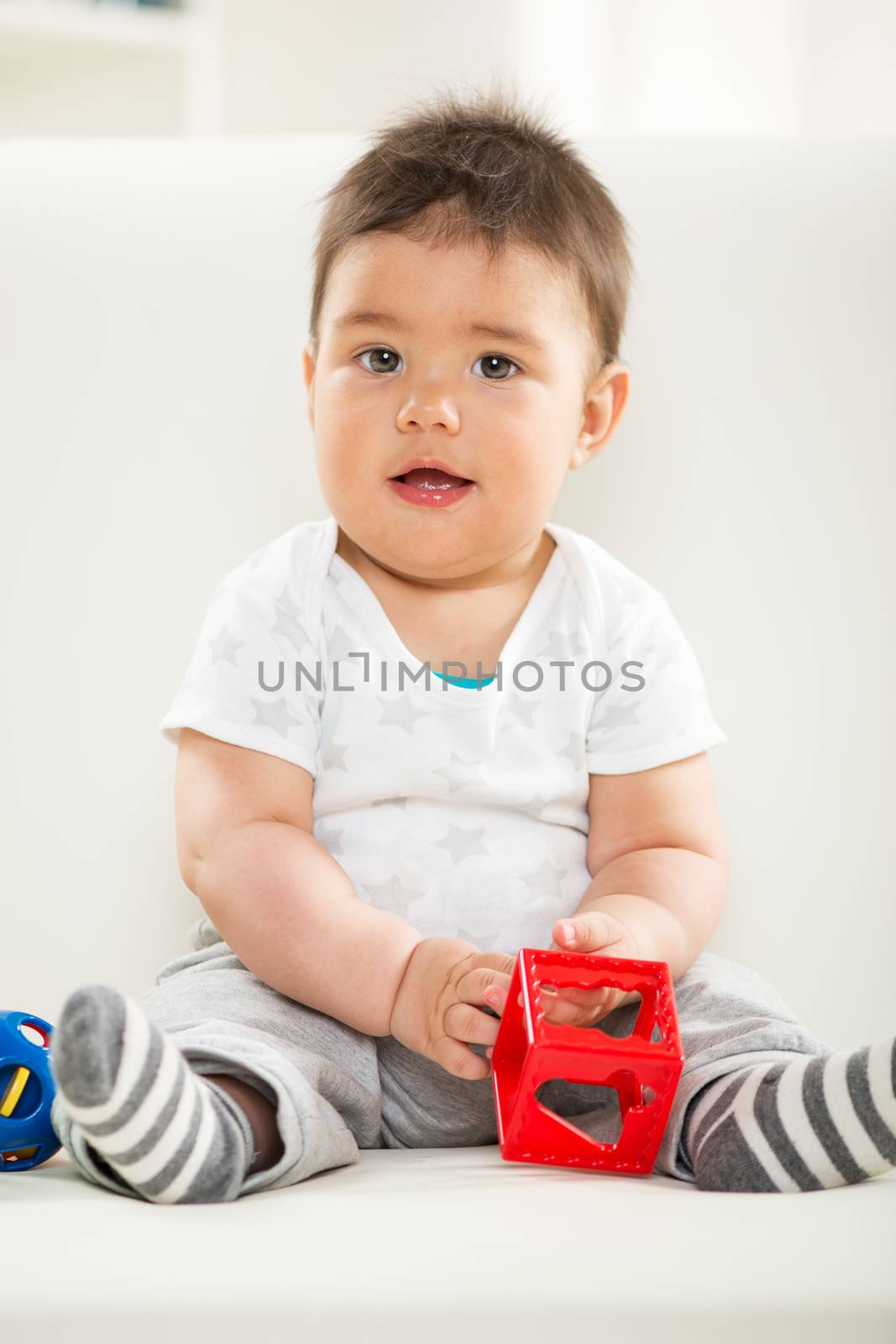 Cute baby boy sitting at home with toy