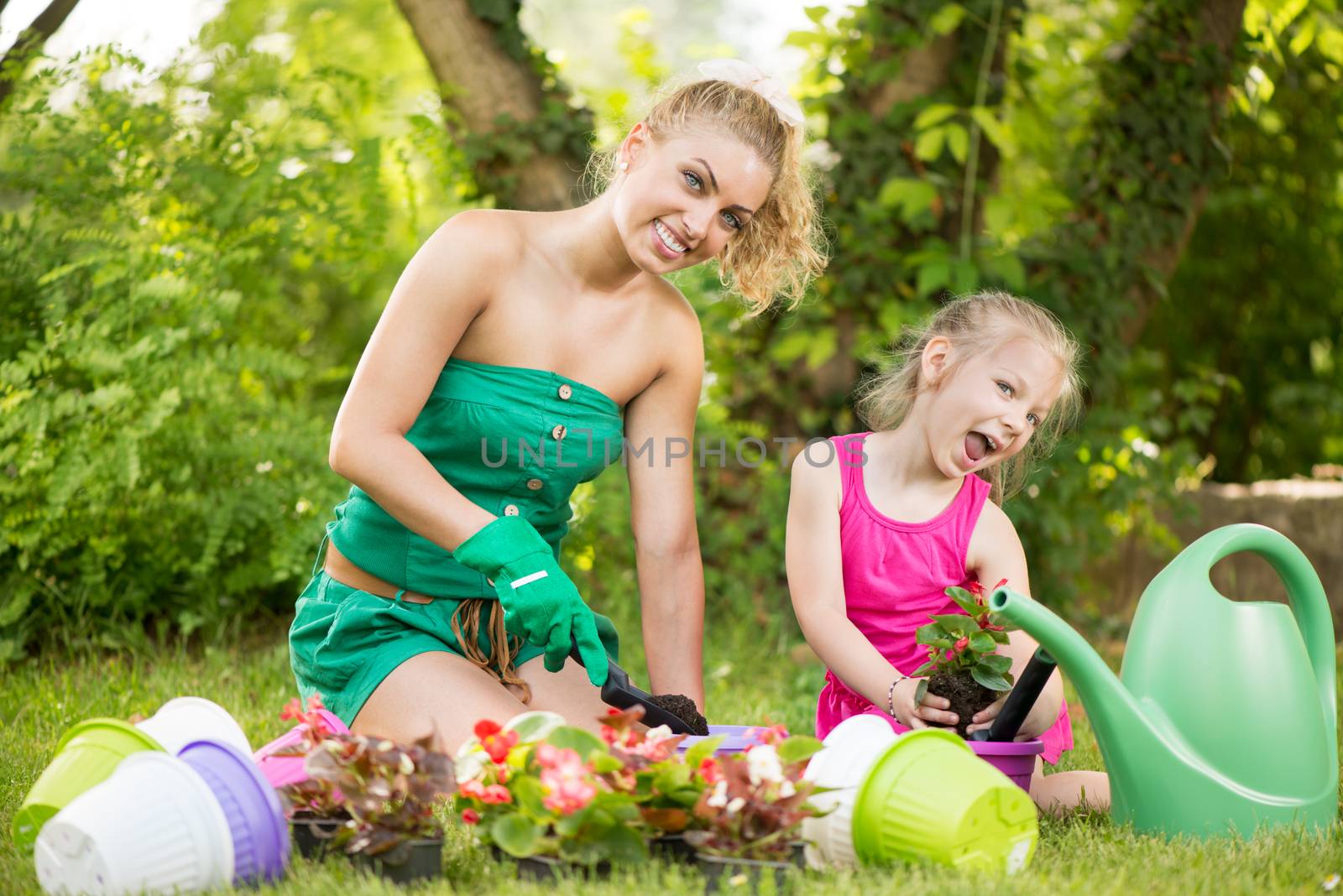 Beautiful mother and daughter planting flowers in the garden.